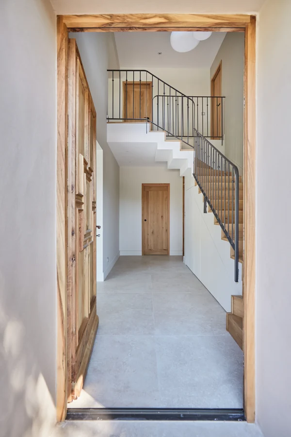 Le hall d'entrée : porte ancienne en bois, escalier en chêne et garde-corps en fer forgé